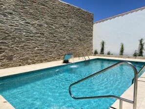 Una piscina al aire libre de temporada, sillones reclinables de piscina