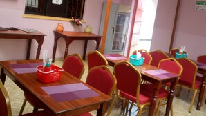 A classroom with wooden desks and red chairs, a blackboard, and a window with a metal grid. - Marra Hill Hotel (Nakuru)