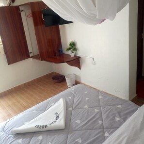 Un dormitorio con una cama, una mesita de noche con una planta, una lámpara colgante y una puerta de madera.