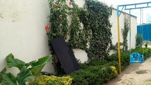 A garden with various plants, a concrete wall, and a blue swing set. - Marra Hill Hotel (Nakuru)