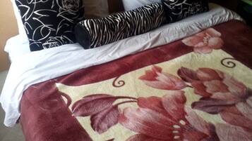 A bed with a floral bedspread, white and black patterned pillows, and a wooden headboard.