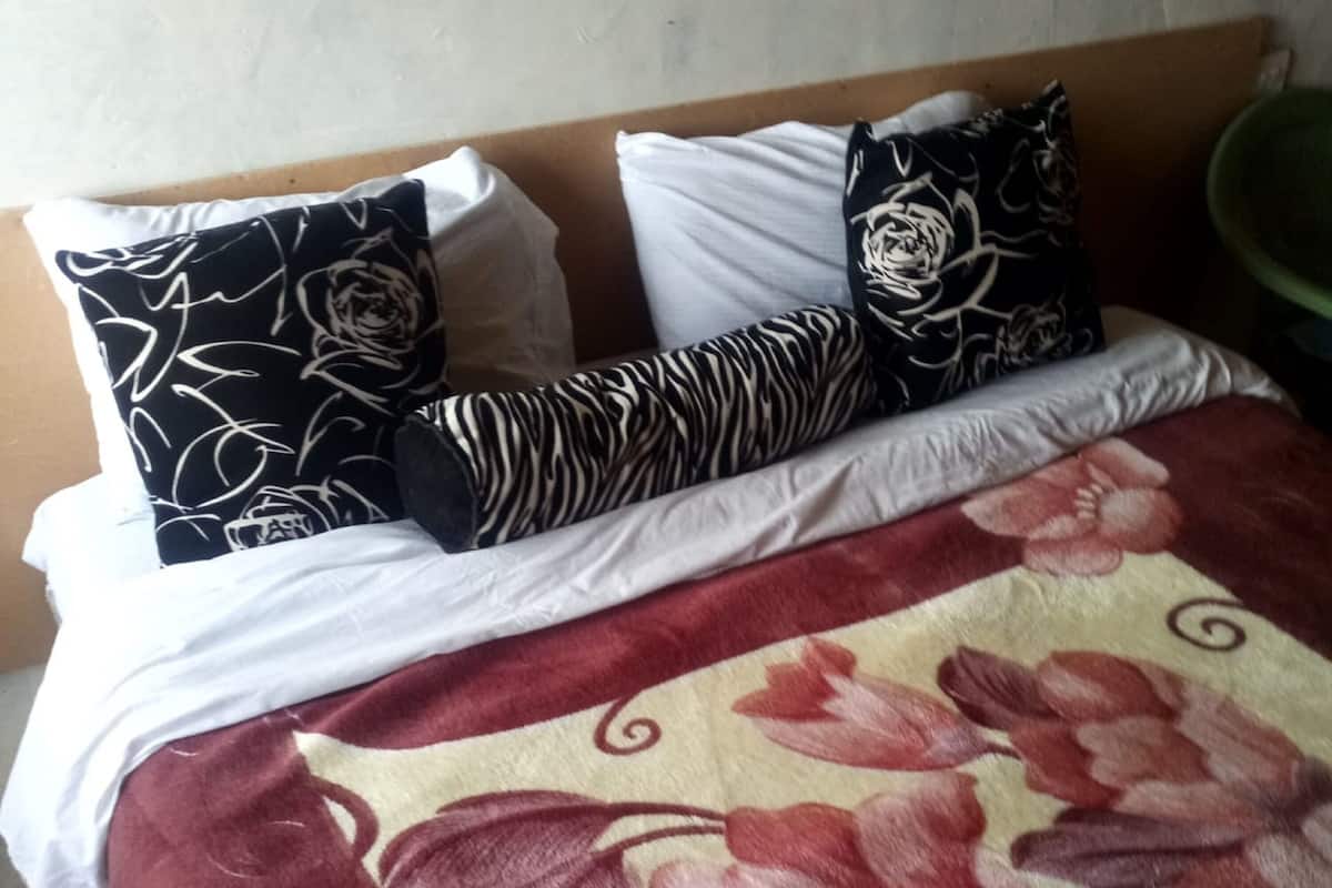 A bed with a floral bedspread, white pillows, and patterned pillows.