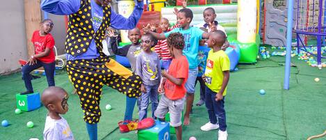 A group of children playing on a colorful playground with various play structures and numbered blocks.