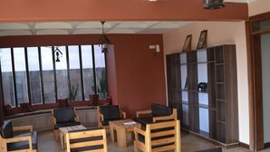 A room with wooden furniture, large windows, and a bookshelf. - Olerai Hotel (Kitengela)