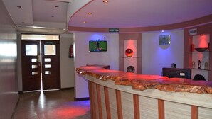 A reception area with a reception desk, a television mounted on the wall, and a reception sign. - Olerai Hotel (Kitengela)