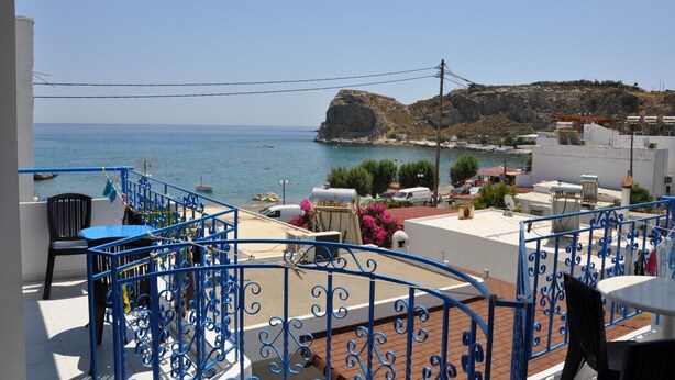 Un balcon avec vue sur la mer et une colline rocheuse.
