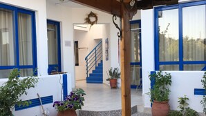 Un bâtiment doté d’un plafond en bois, de fenêtres à cadre bleu et d’un escalier menant à l’étage supérieur.