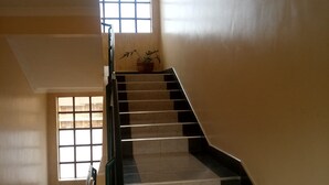 A staircase with a handrail, leading to a landing with a potted plant. - Remiz Guest House (Nakuru)