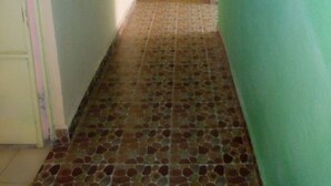 A narrow hallway with a tiled floor and green walls. - Peacock Restaurant (Nyeri)