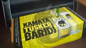 A bar stool with a Kamata Tusker Barid beer advertisement. - Peacock Restaurant (Nyeri)