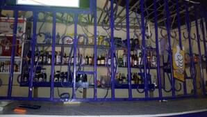 A bar with a blue metal railing and shelves stocked with various bottles. - Peacock Restaurant (Nyeri)