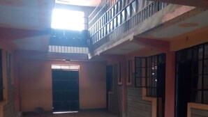 An interior with a central open space, a balcony, and a door leading to another room. - Puya Lodge (Kitengela)