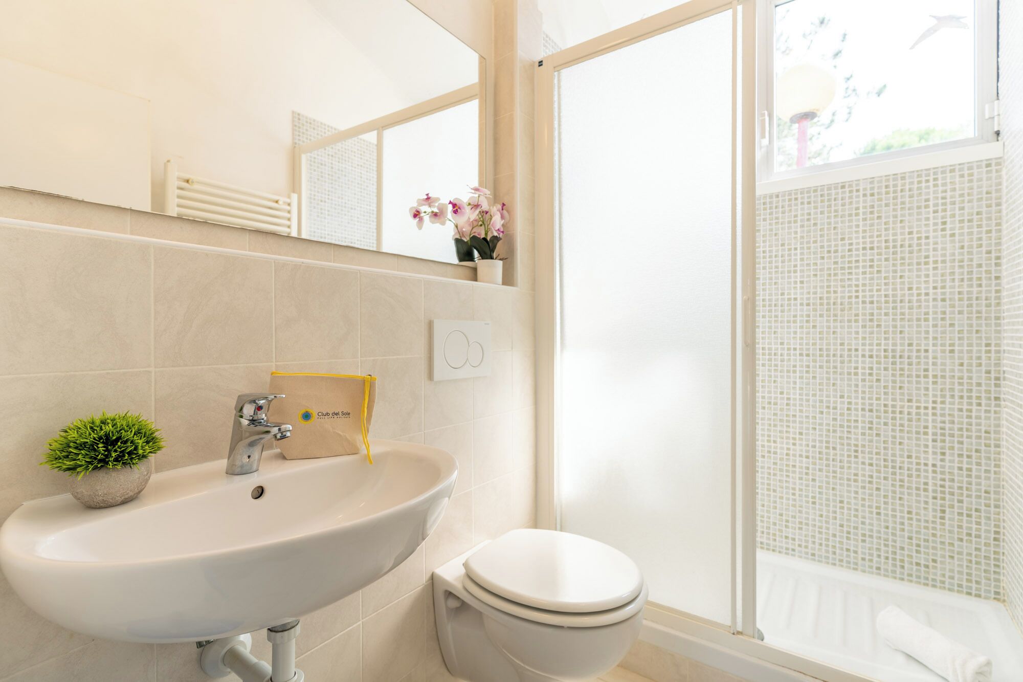 A bathroom with a sink, toilet, and a window with a view.