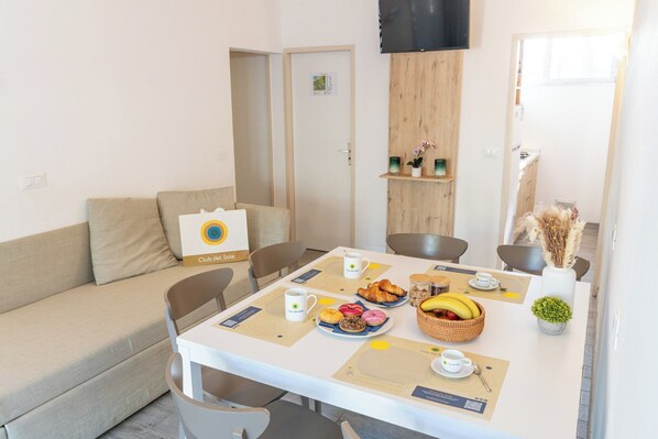 Un comedor con una mesa dispuesta para el desayuno, incluyendo cruasanes, bollería y fruta.