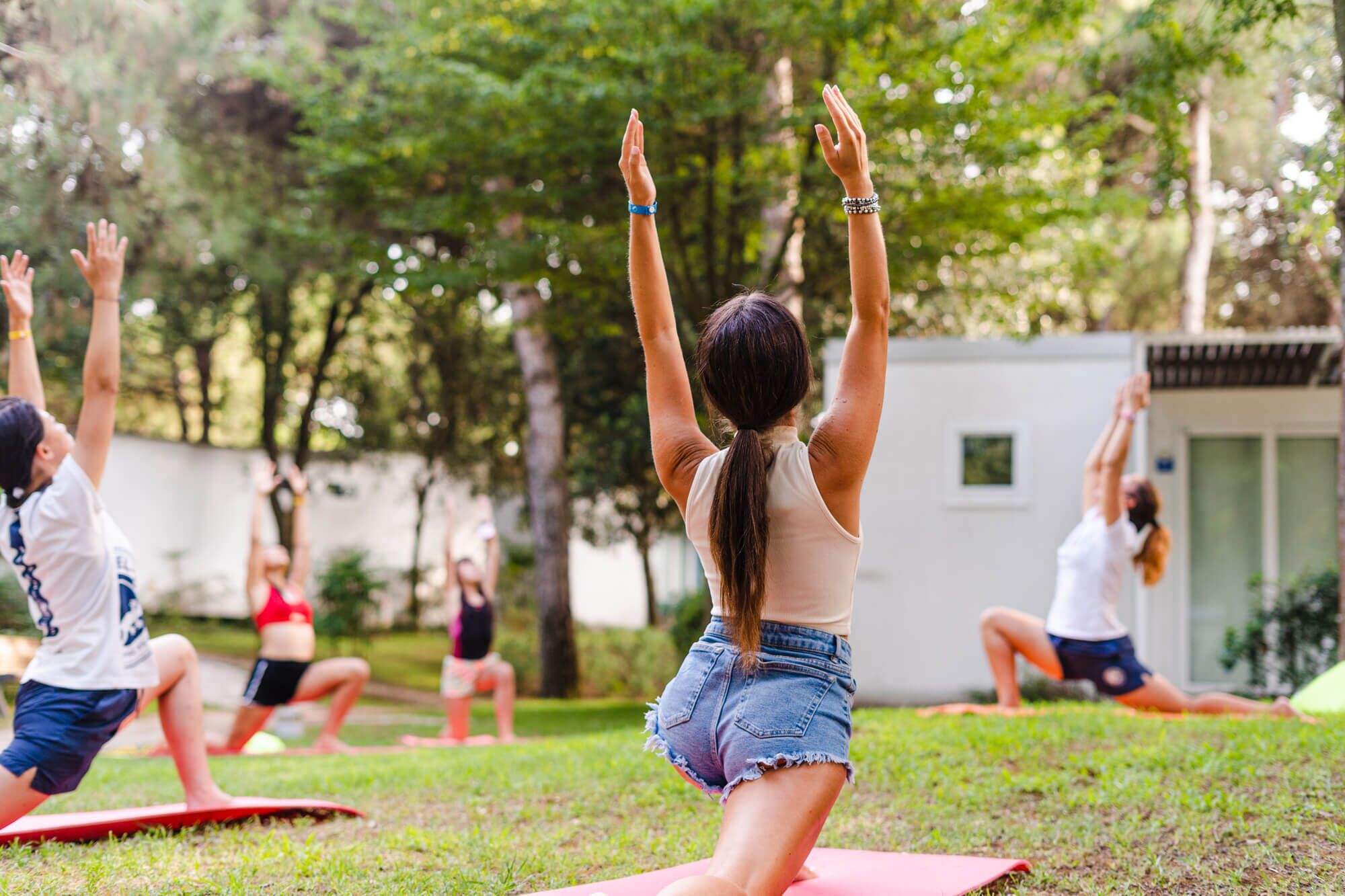 En gruppe mennesker dyrker yoga udendørs på en græsplæne.