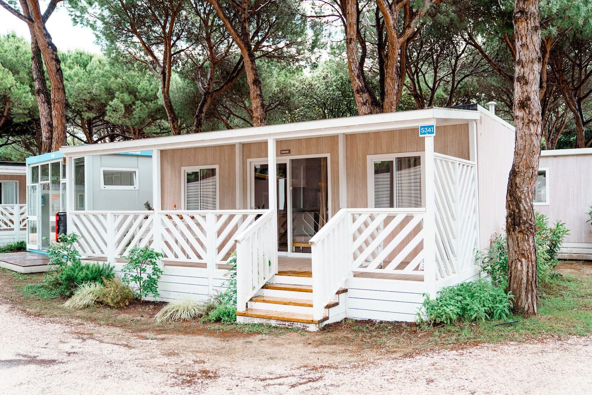 Une maison mobile dotée d’une véranda, d’un escalier et d’un panneau indiquant le numéro de la maison.