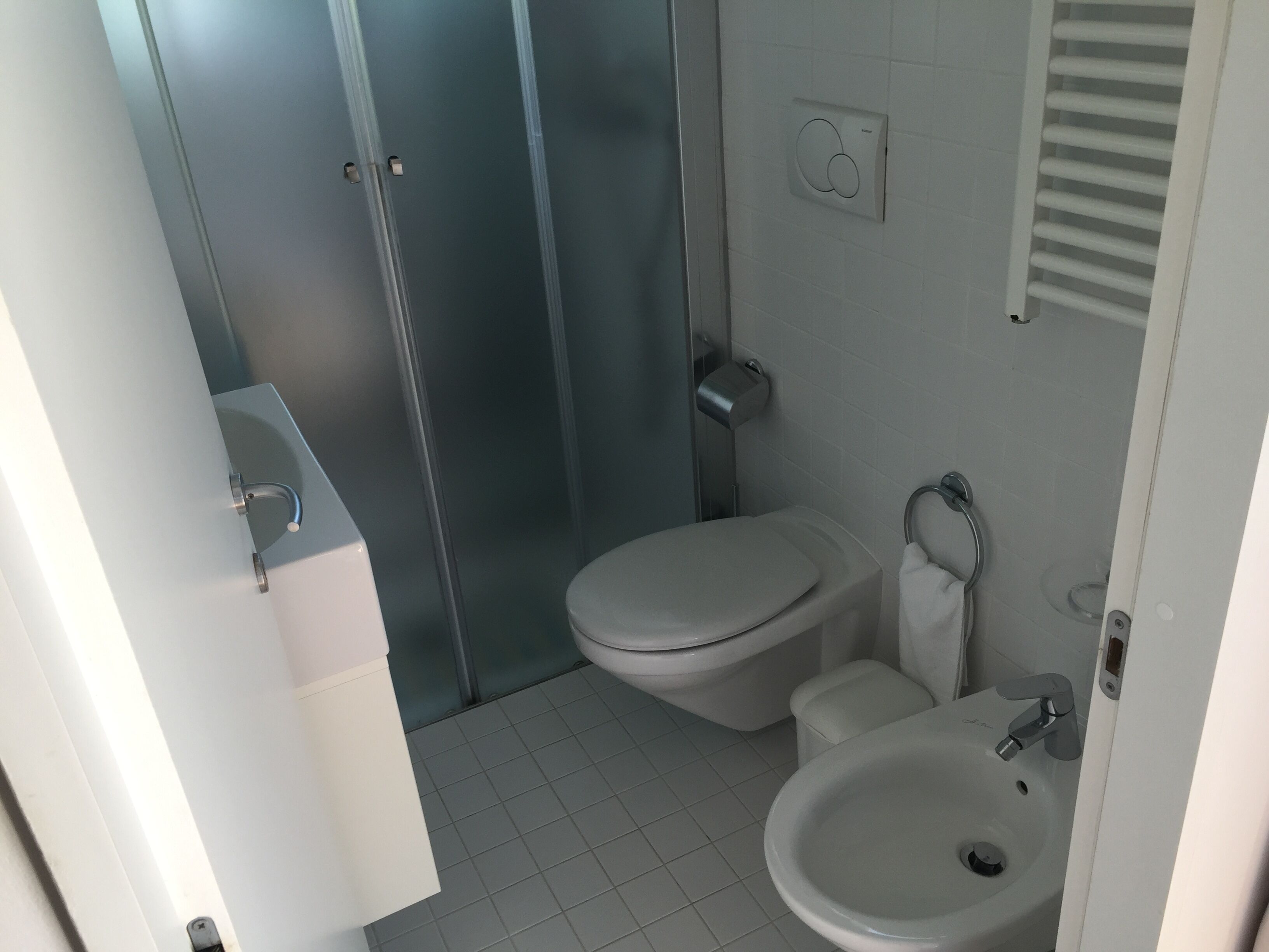 A bathroom with a toilet, sink, and shower area.
