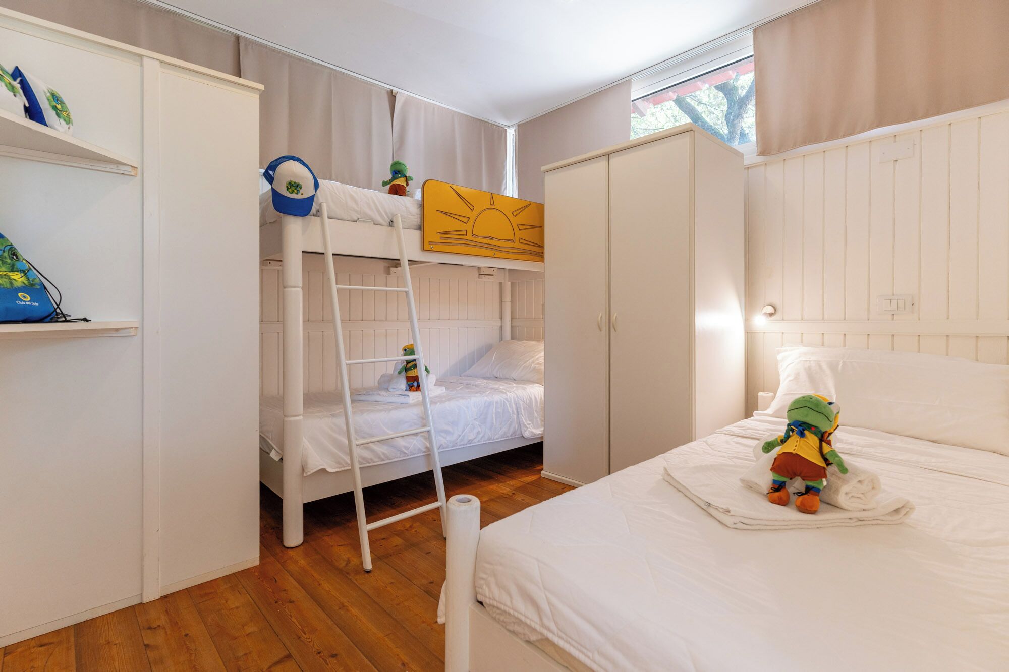 Una habitación con literas, un armario y una cama con un peluche.