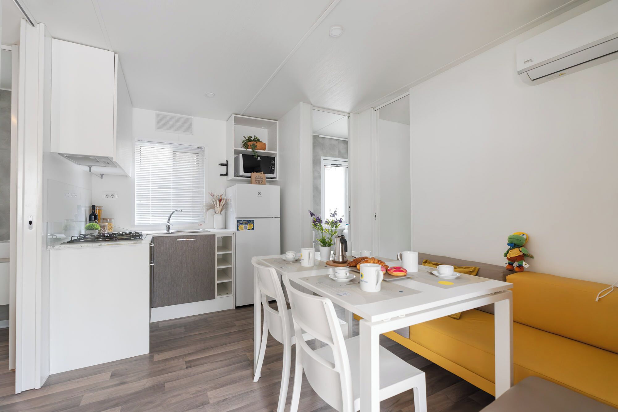 A compact kitchen with a dining area, a sofa, and a small table.