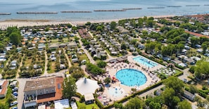 An aerial view of a vacation area with a large swimming pool, beach, and numerous mobile homes.
