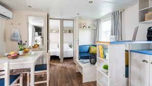 A compact, well-lit room with a kitchenette, a dining area, and a seating space with a laptop and books. - Club del Sole Vigna sul Mar Family Collection (Comacchio)