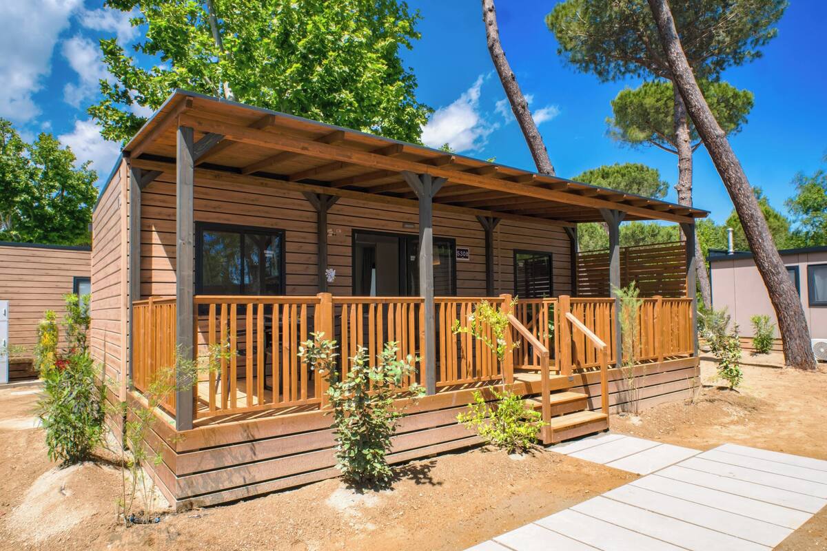 A wooden cabin with a wooden deck and a covered porch.