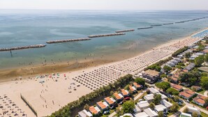 A beach with a row of mobile homes, a sandy beach, and a calm sea. - Club del Sole Vigna sul Mar Family Collection (Comacchio)