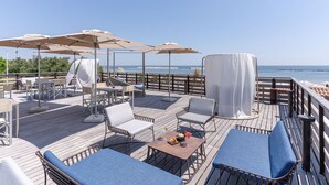 A deck with outdoor seating, umbrellas, and a view of the sea. - Club del Sole Vigna sul Mar Family Collection (Comacchio)
