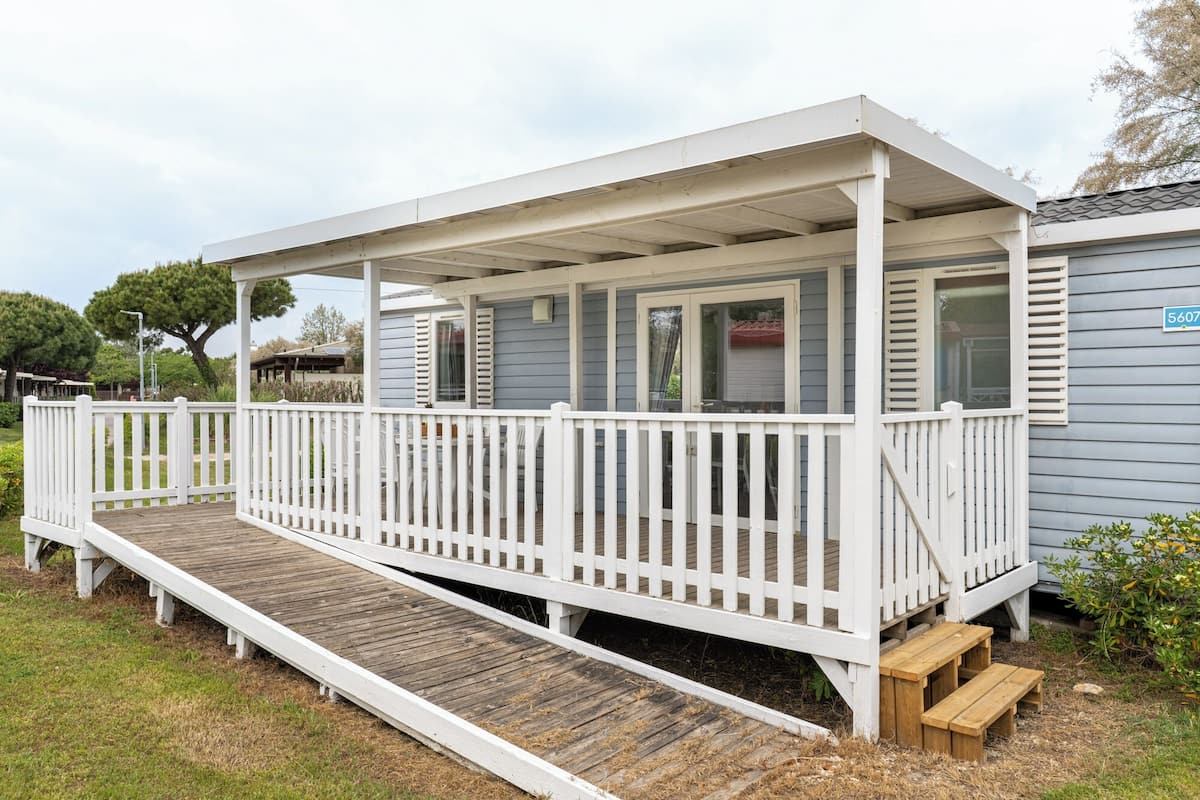 A covered porch with a white railing, wooden steps, and a small wooden bench.