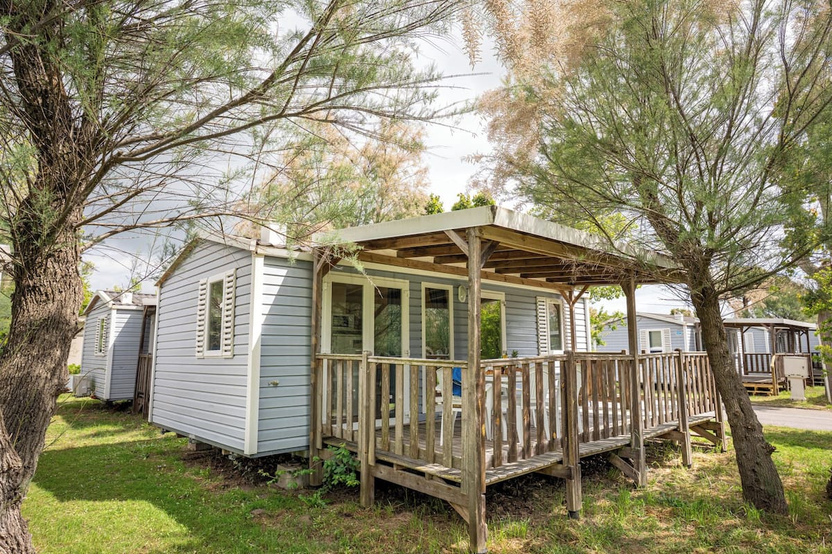 A small cabin with a porch, surrounded by trees.