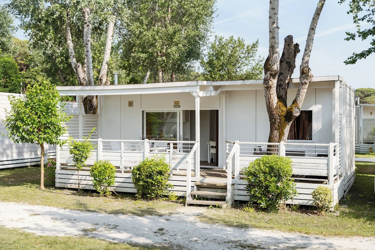 A white mobile home with a porch, a small deck, and a number '514' sign.