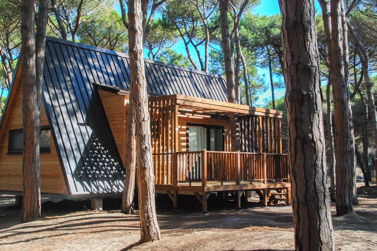 A cabin with a sloped roof, wooden deck, and a window.