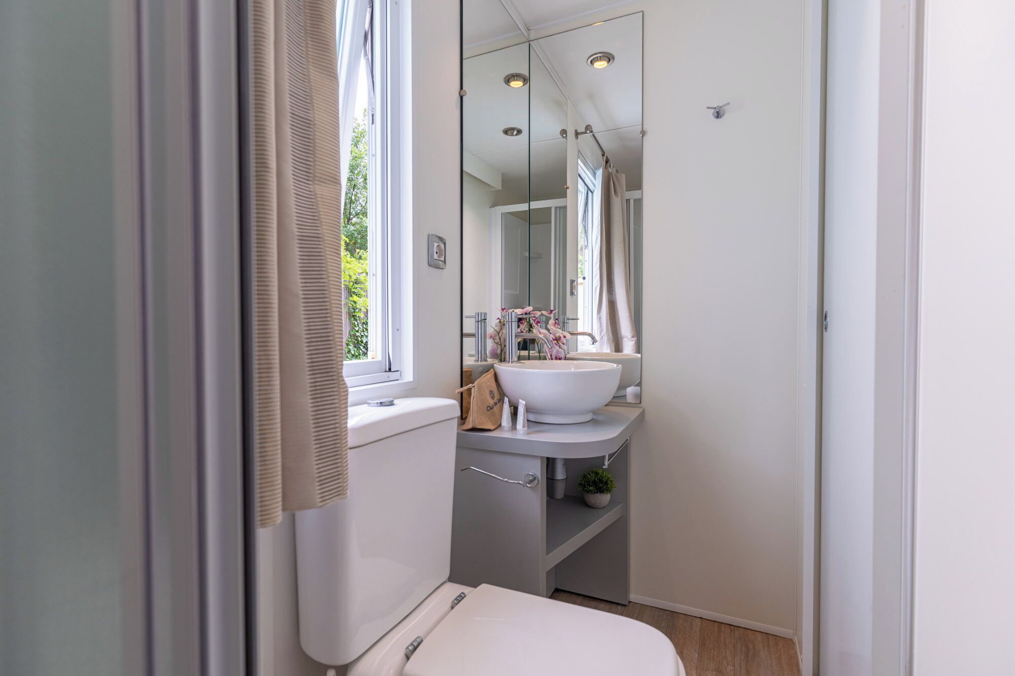 A compact bathroom with a toilet, sink, and mirror.