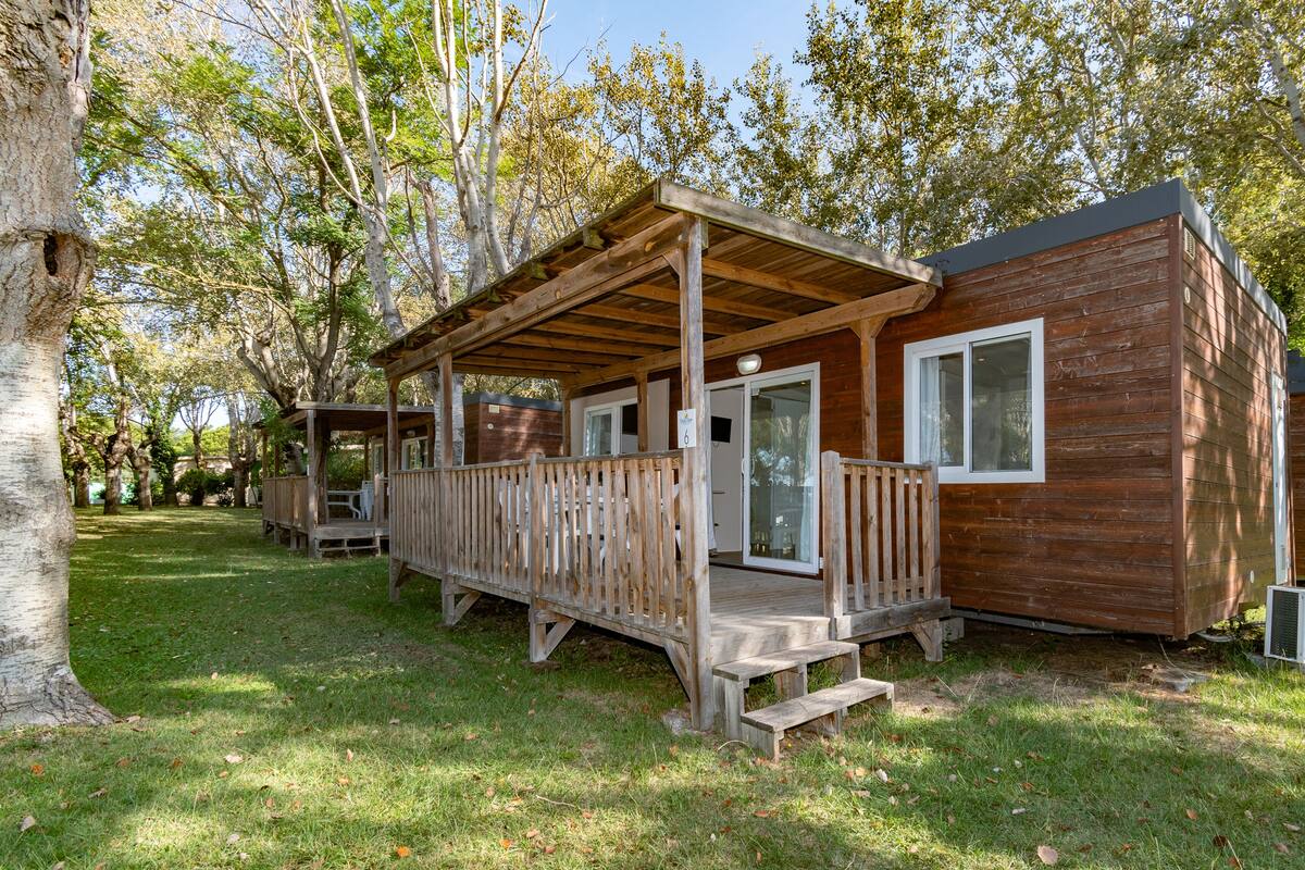 A wooden cabin with a porch, large windows, and a covered deck.
