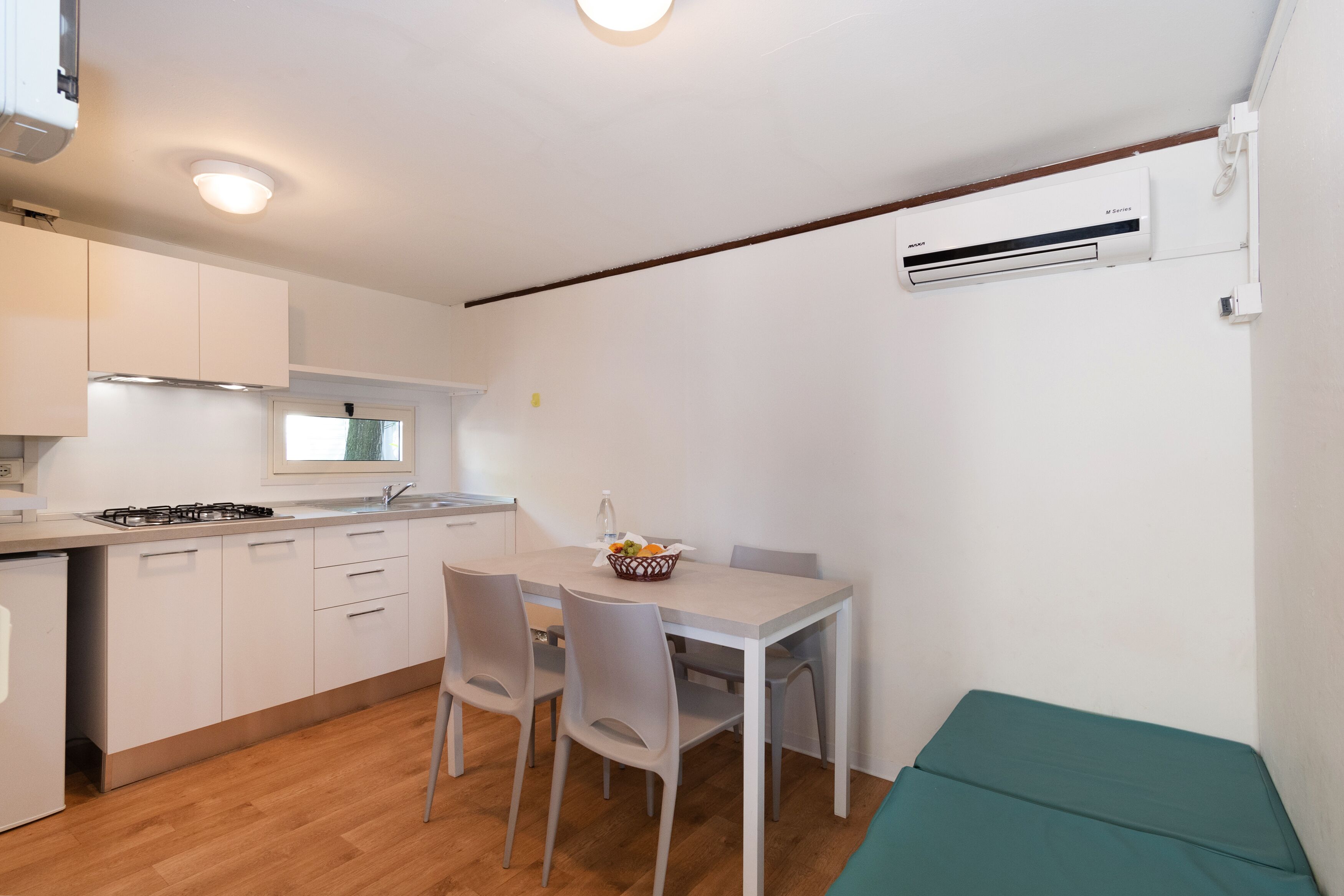 A compact kitchen with white cabinets, a gas stove, and a dining area with a table and chairs.