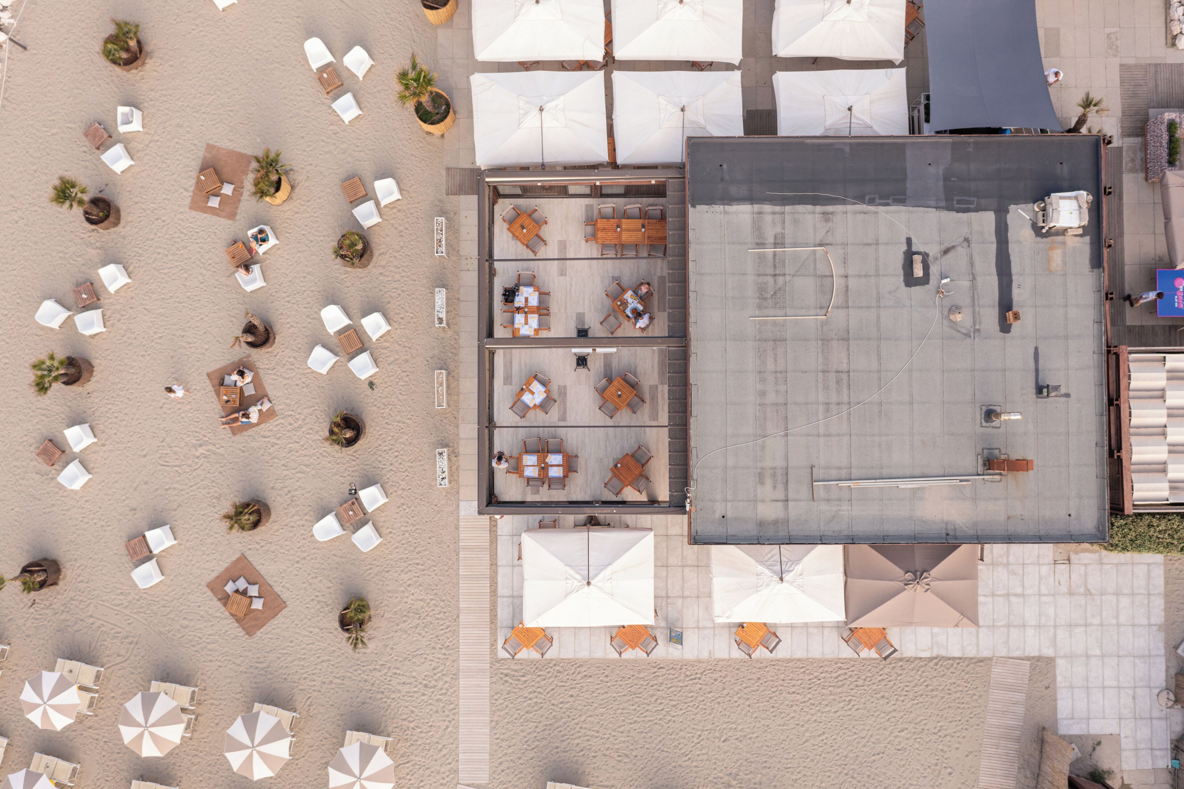 An aerial view of a rooftop terrace with sun loungers, umbrellas, and tables.