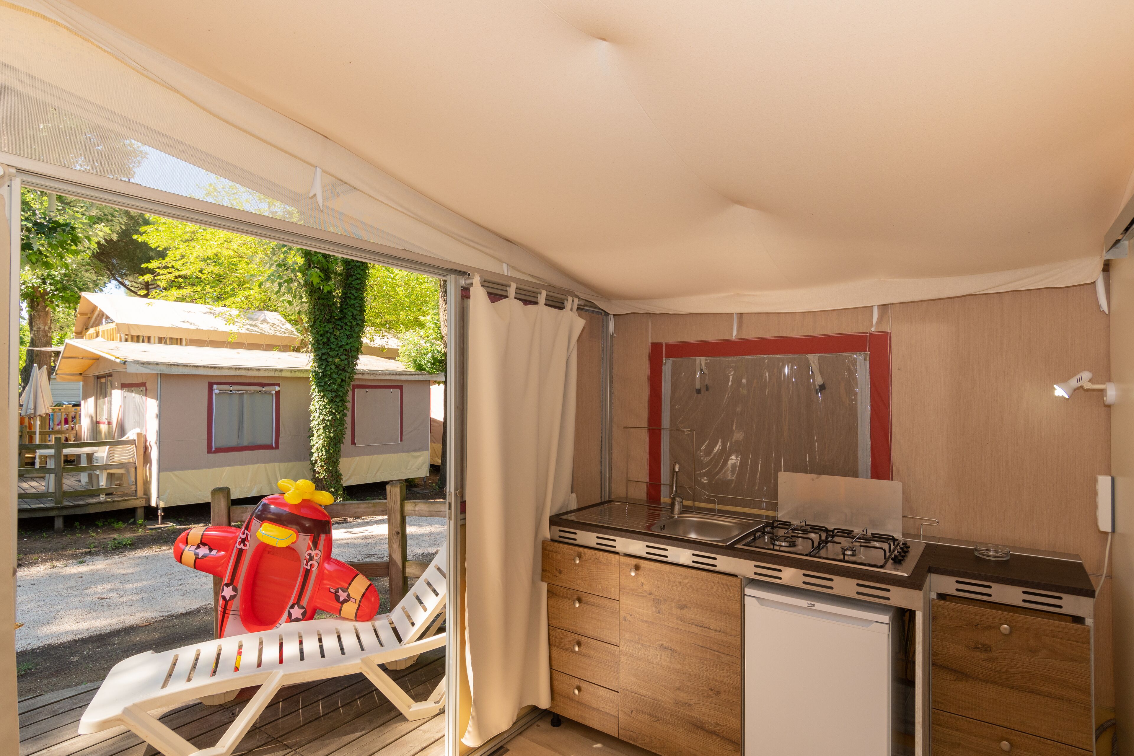 A compact kitchen with a gas stove, a small refrigerator, and a wooden cabinet.