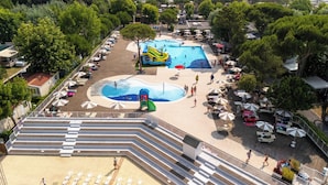 A pool area with multiple swimming pools, a children's play area, and sun loungers. - Club Del Sole Marina Family Resort (Ravenna)