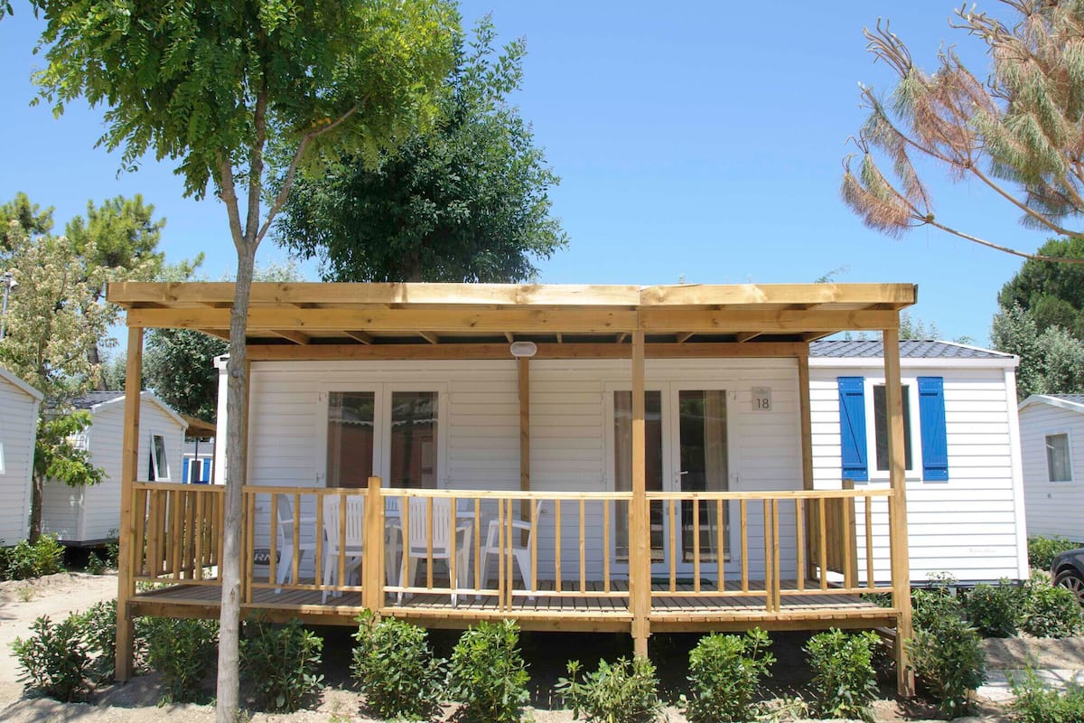 A mobile home with a wooden deck, a covered porch, and a number '18' on the side.