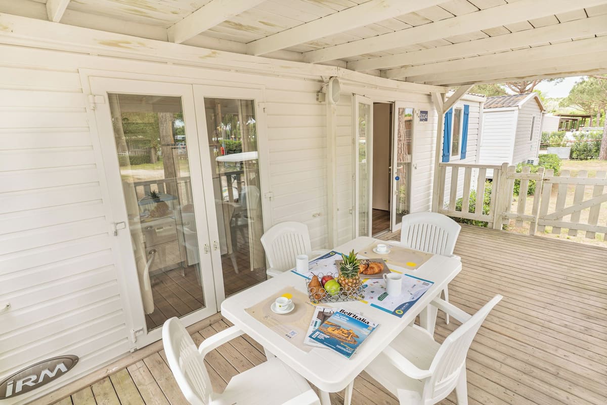A covered outdoor seating area with a table, chairs, and a magazine.