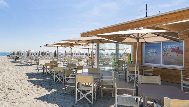 A beachside restaurant with outdoor seating, umbrellas, and a view of the sea. - Club Del Sole Marina Family Resort (Ravenna)