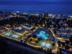 Luftaufnahme eines Resorts mit mehreren Schwimmbecken, einem Strand und einer Marina.