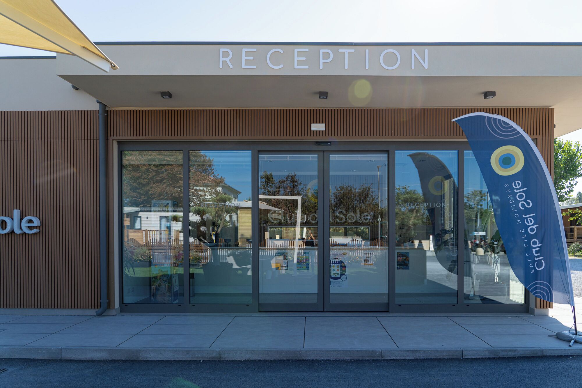 A reception area with a modern design, featuring a large glass entrance and a wooden facade.