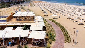 Un resort in riva al mare con una lunga passeggiata, aree salotto all'aperto e vista sulla spiaggia.