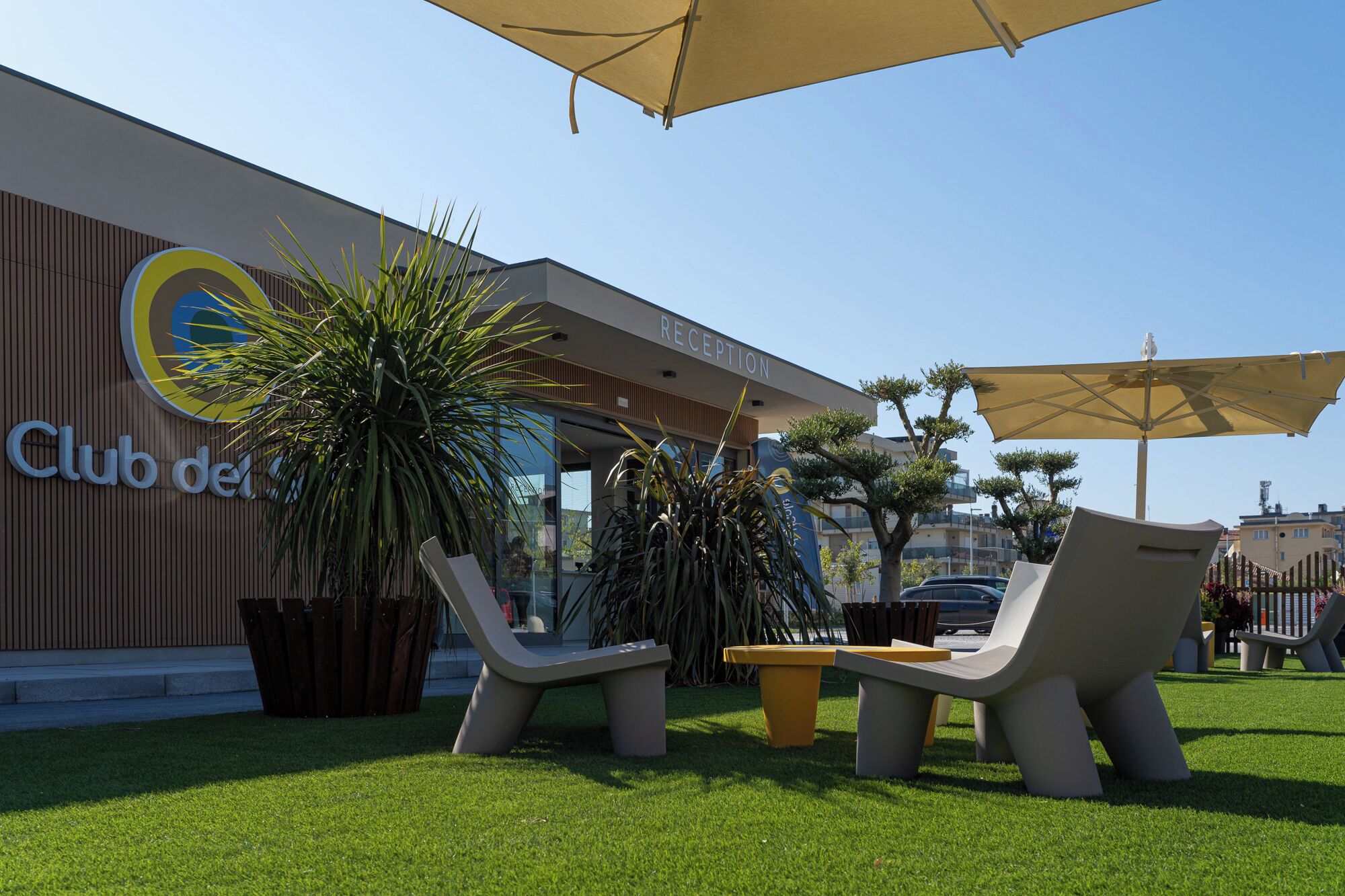 A Club del Rey reception area with outdoor seating and a large potted plant.