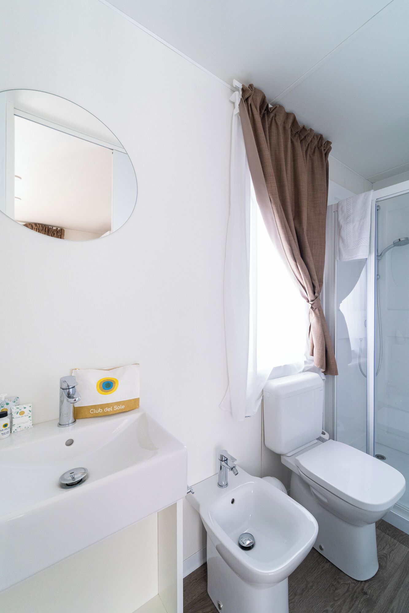 A modern bathroom with a bidet, a sink, and a mirror.