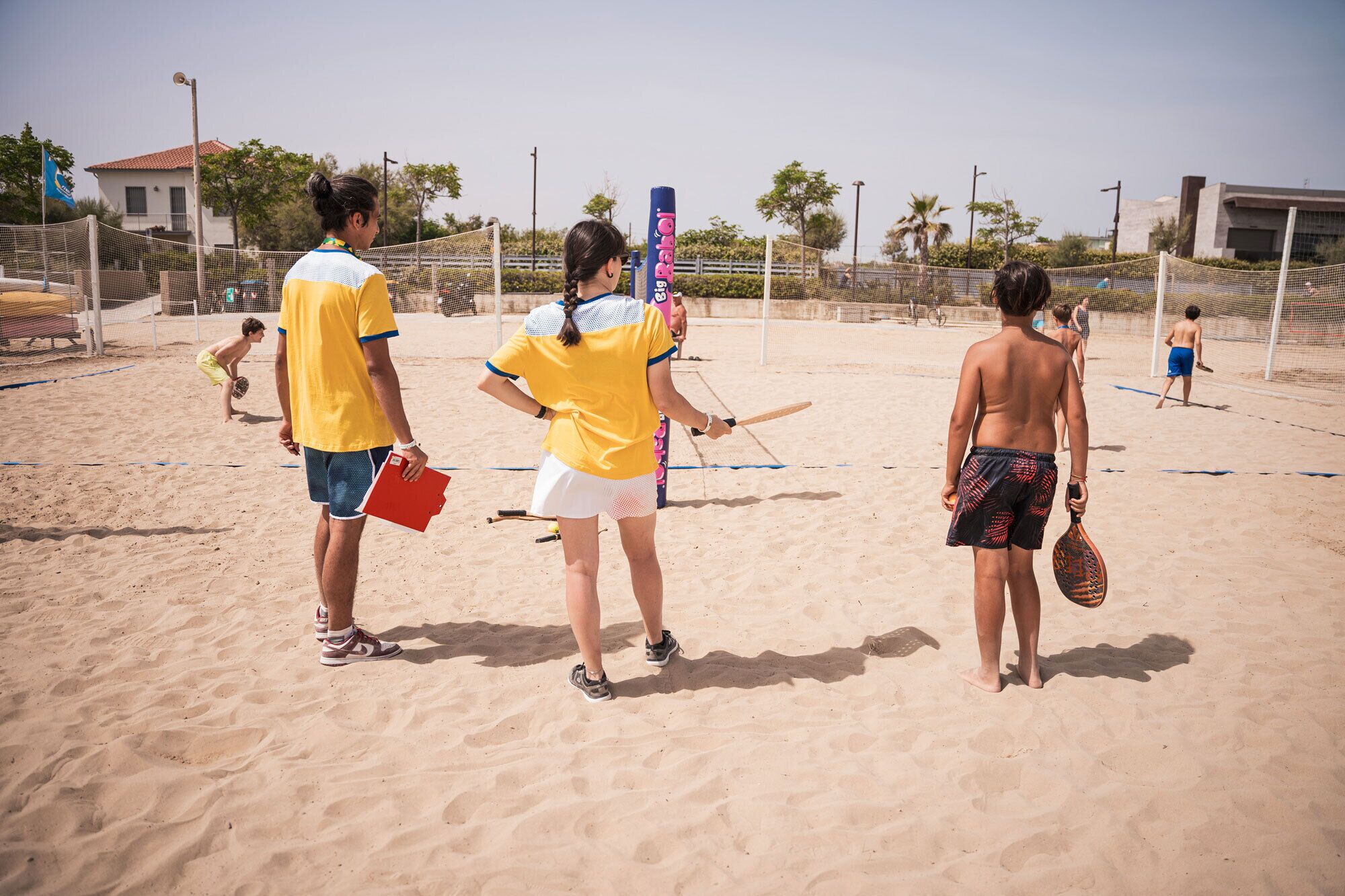 Uma quadra de voleibol de praia com jogadores, rede e bola.
