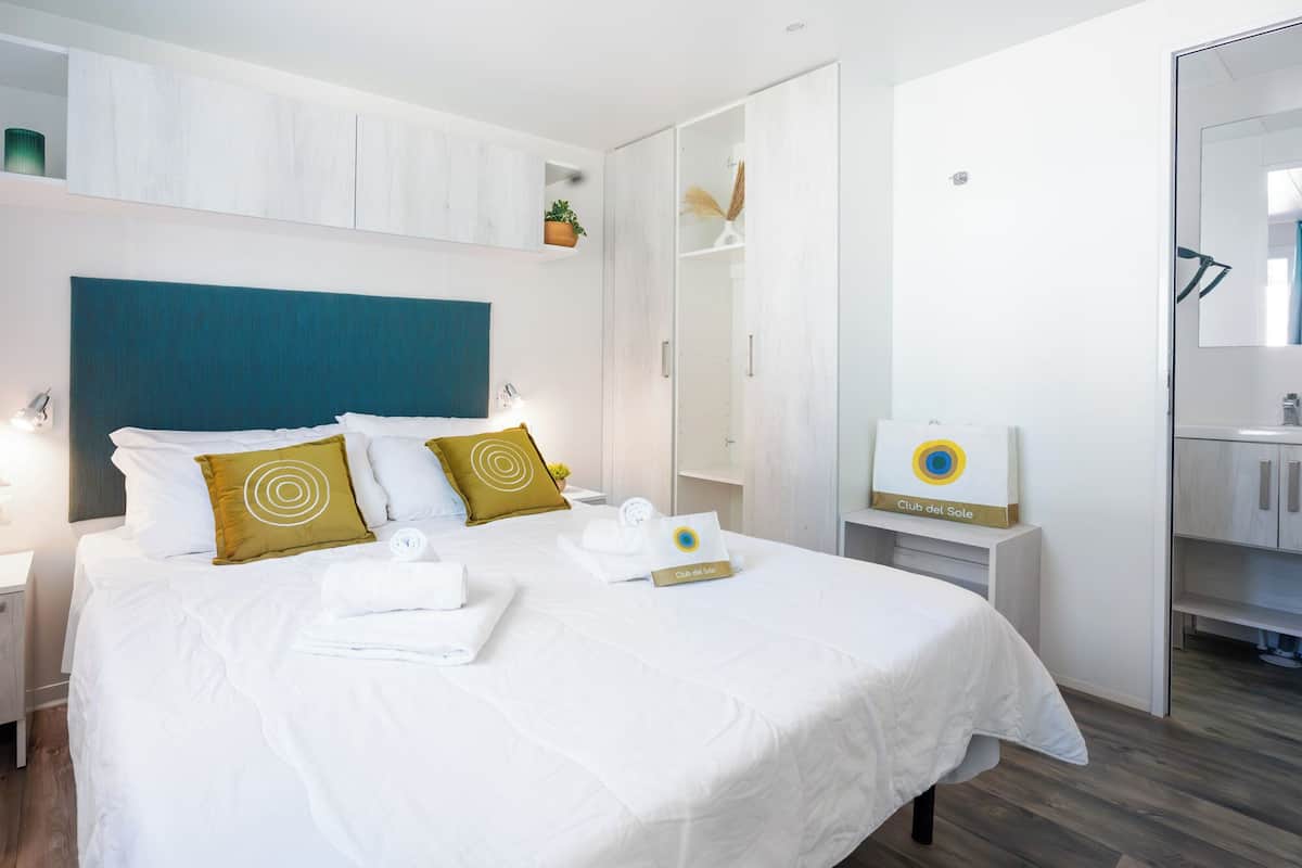 A hotel room with a bed, a nightstand, a mirror, a wardrobe, and a bathroom.
