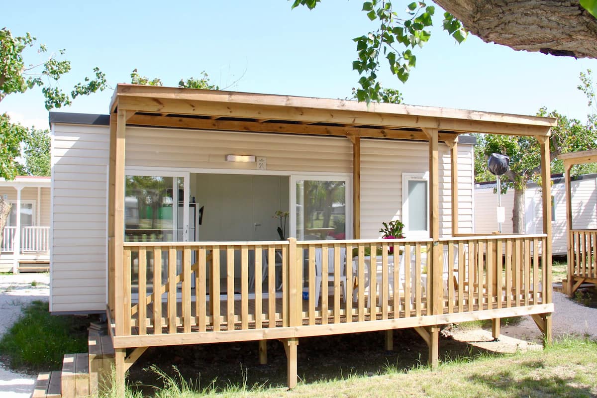 A mobile home with a wooden deck and a covered porch.