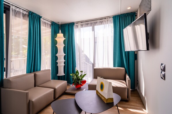 A modern living room with a sofa, armchair, and a coffee table. There is a potted plant and a shopping bag on the table. - Club del Sole Romagna Family Village Riccione. (Riccione)